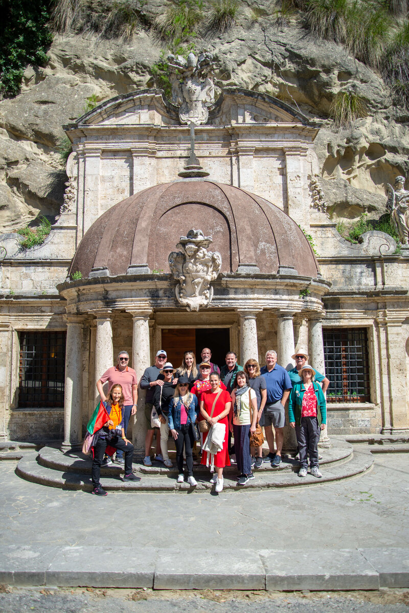 A group of people poses in front of an ancient Italian structure On the Italian on Tour’s 10 day Epicurean Journey trip through Italy––